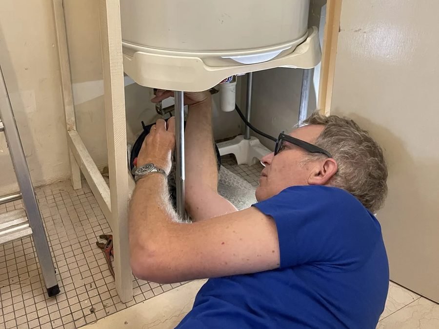 Plombier intervenant sous un chauffe-eau